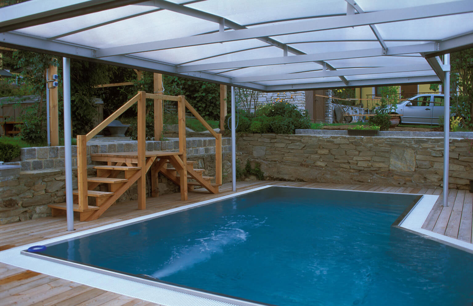 LOWO Sonnenlift - Hochwertige Schwimmbadüberdachungen Beispiel einer LOWO Sonnenlift Schwimmbadüberdachung in einem Garten.
